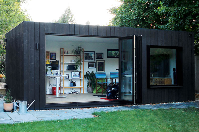 Modern minimalist prefab container house in a backyard, dark grey and red exterior steel modular pod